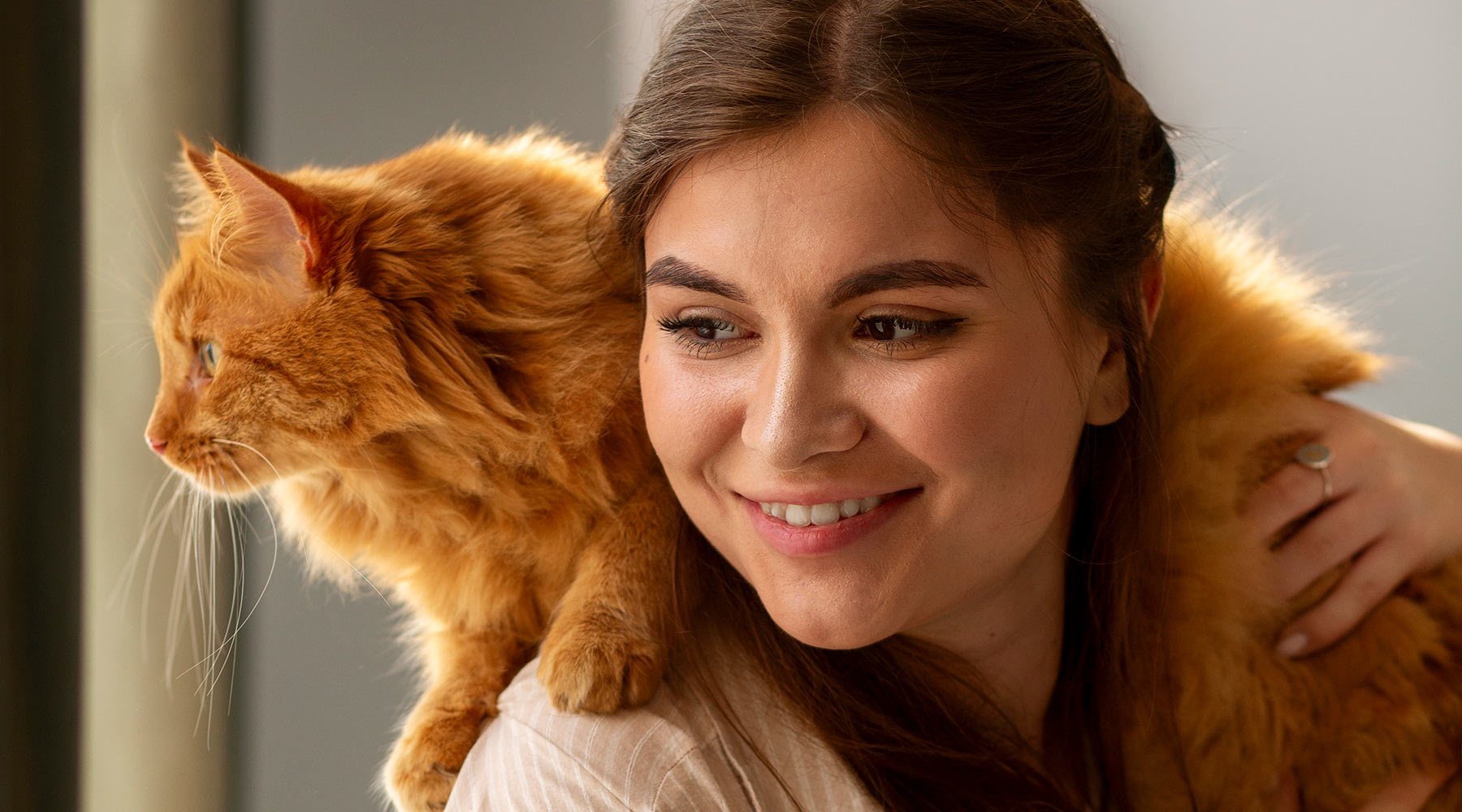 smiling-woman-carrying-orange-cat-on-shoulder-1800x1000-1